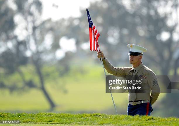 Marine waits to inserts a pin flag with a American flag into the cup at the 11th green during the third round of the Farmers Insurance Open held at...