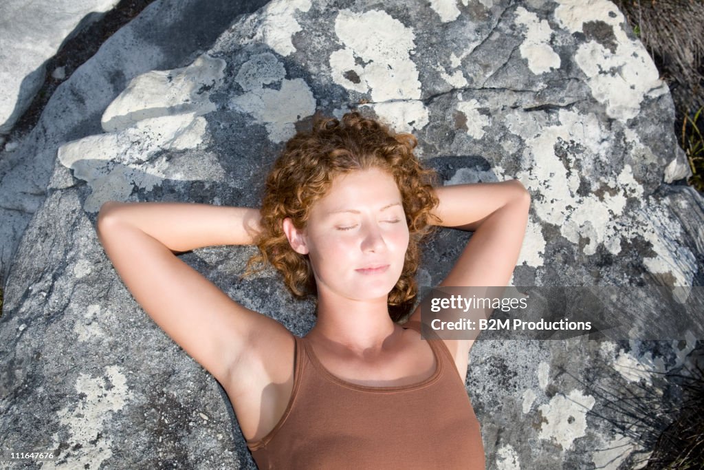 Woman sleeping on rock