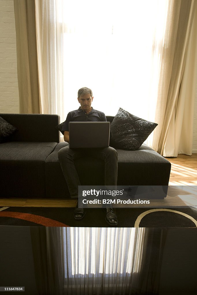 Young man sitting on sofa using laptop