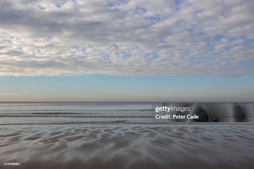 Beach with reflection of sky in sand