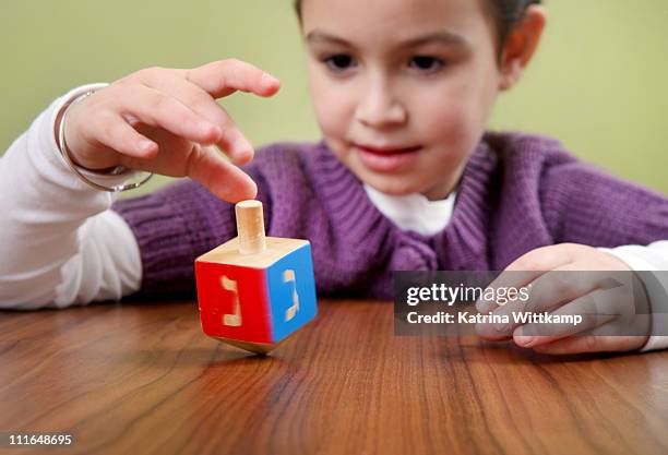 girl spins a dreidel. - dreidel stockfoto's en -beelden