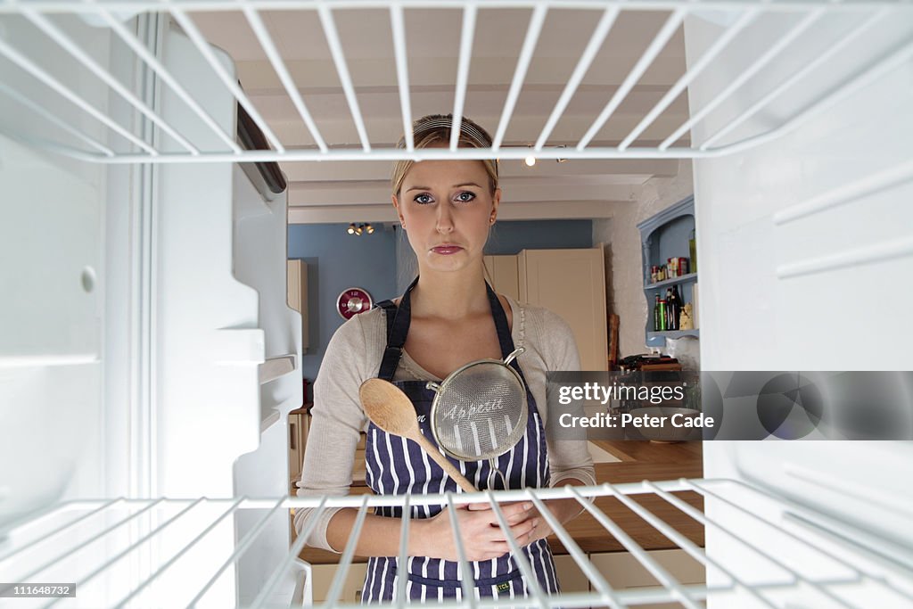 Woman ready to cook looking into empty fridge