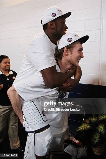 Kemba Walker of the Connecticut Huskies rides on the back of teammate Niels Giffey as they walk off the court after defeating the Butler Bulldogs to...