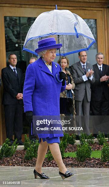 Britain's Queen Elizabeth II walks in the rain, holding her umbrella, during her visit to the new National Tennis Centre, Roehampton, in London, 29...