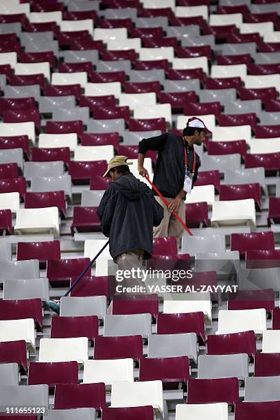 Workers clean the stadium at the end of the 2011 Asian Cup semi-final football match between Australia and Uzbekistan in the Qatari capital Doha on...