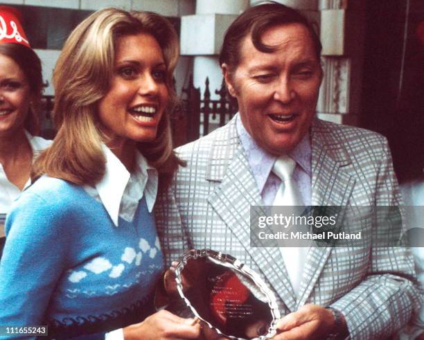 Singer Olivia Newton John presenting an award from MCA Records, to American rock and roll singer and guitarist Bill Haley , London, 1974. The award...