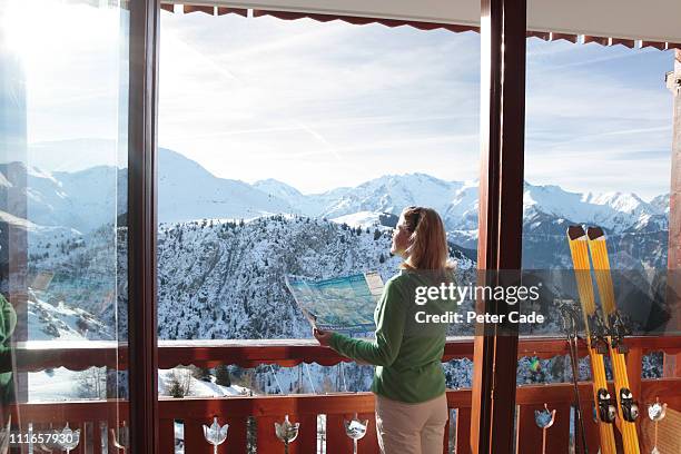 woman looking out of window at ski slopes - pista da sci foto e immagini stock