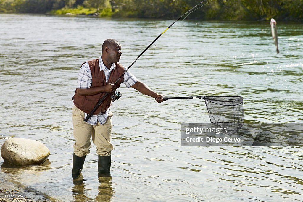 Black Man With Net Catching Fish In Stream High-Res Stock Photo - Getty  Images