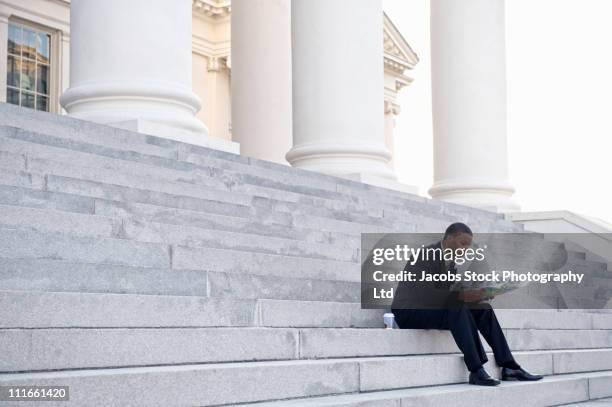 african american businessman reading newspaper on steps of courthouse - government worker stock pictures, royalty-free photos & images