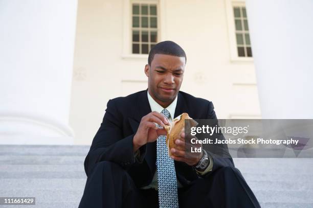 african american businessman eating sandwich on courthouse steps - disgusto foto e immagini stock