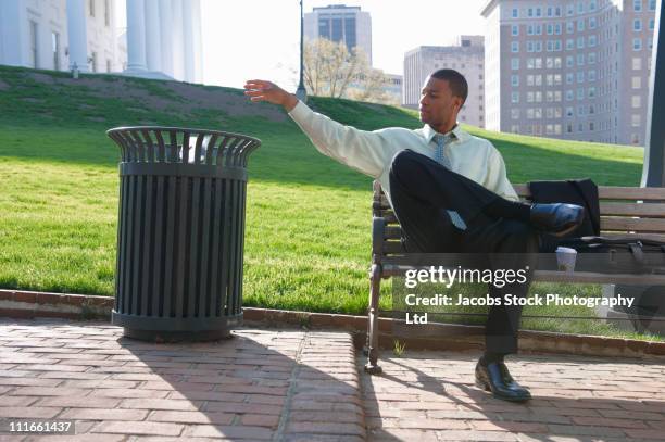african american businessman throwing trash in garbage can - dustbin stock pictures, royalty-free photos & images