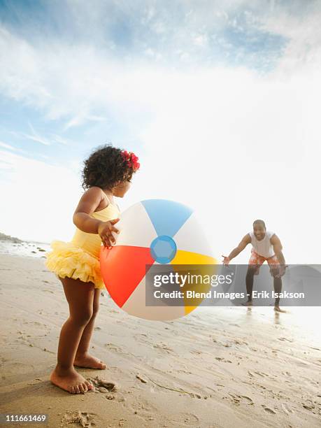 black father throwing ball on beach with daughter - beach ball stock pictures, royalty-free photos & images