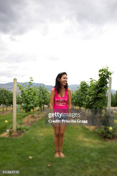 smiling hispanic woman standing in vineyard - okanagan vineyard stockfoto's en -beelden