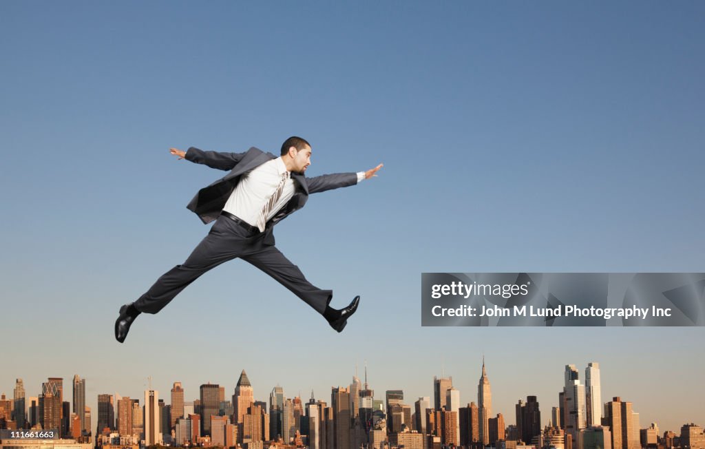 Businessman jumping over highrise buildings