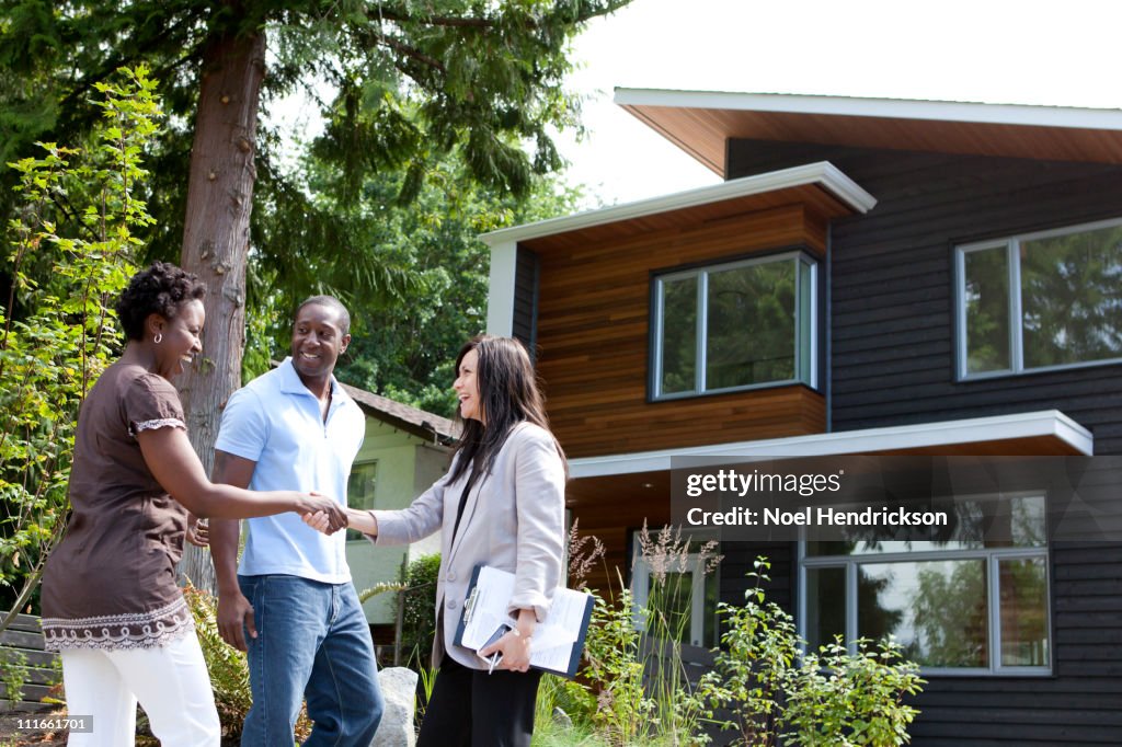 Real estate agent greeting couple at house