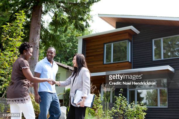 real estate agent greeting couple at house - real estate agent stock pictures, royalty-free photos & images