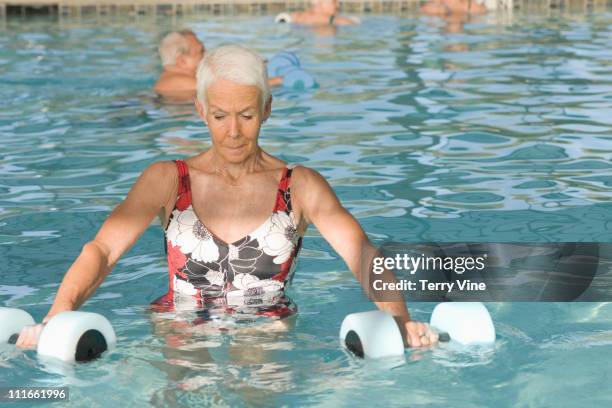 caucasian woman exercising in swimming pool - aqua aerobics stockfoto's en -beelden