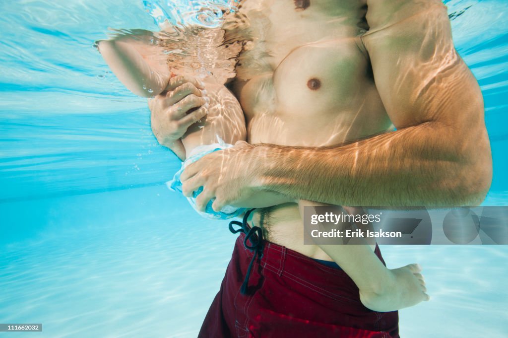 Mixed race father holding daughter in swimming pool