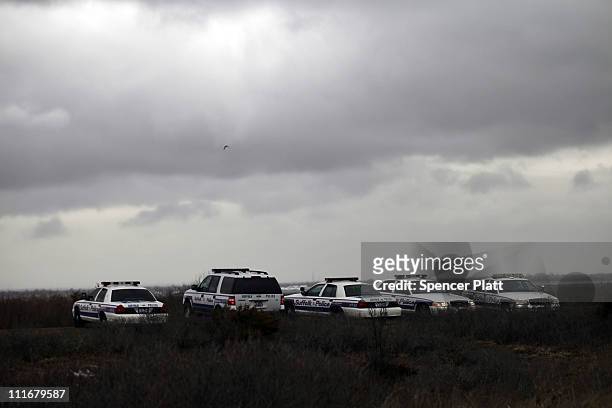 Suffolk County Police cars involved in the search effort are parked on the side of the road along a stretch of beach highway where police recently...