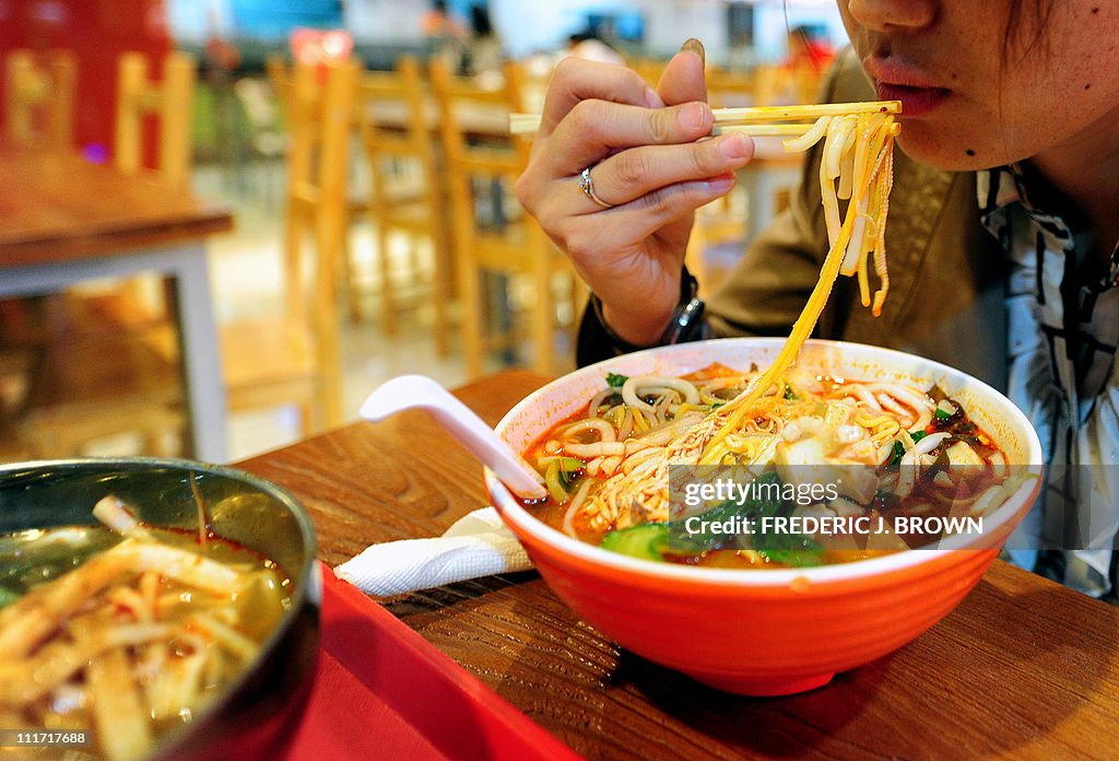 A woman lunches on a bowl of soup noodle