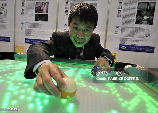 Southern Taiwan University's Tang Jing-Jou poses with his invention, a billards table with trajectory recording capabilities during the opening day...