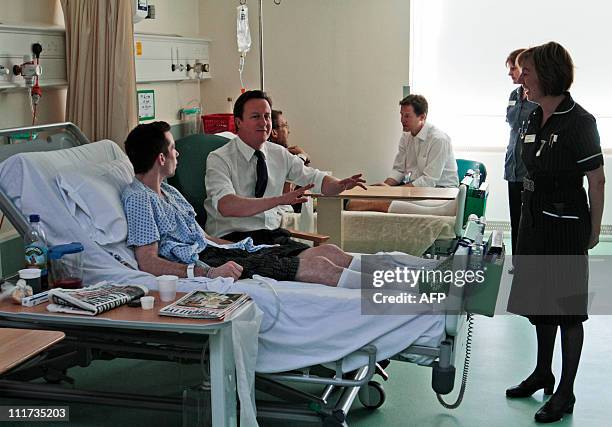 Britain's Prime Minister David Cameron talks with patient Aiden Ostinelli as Deputy Prime Minister Nick Clegg talks to another patient during a visit...