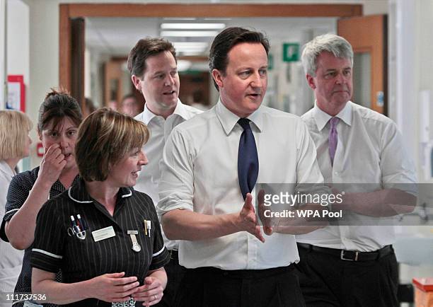 Britain's Prime Minister David Cameron, center, accompanied by Deputy Prime Minister Nick Clegg, background left, and Health Secretary Andrew...