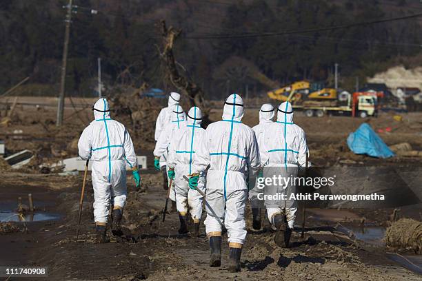 Japanese policemen in protective suites search for missing people, within the exclusion zone, about 20 kilometers away from Fukushima Nuclear Power...