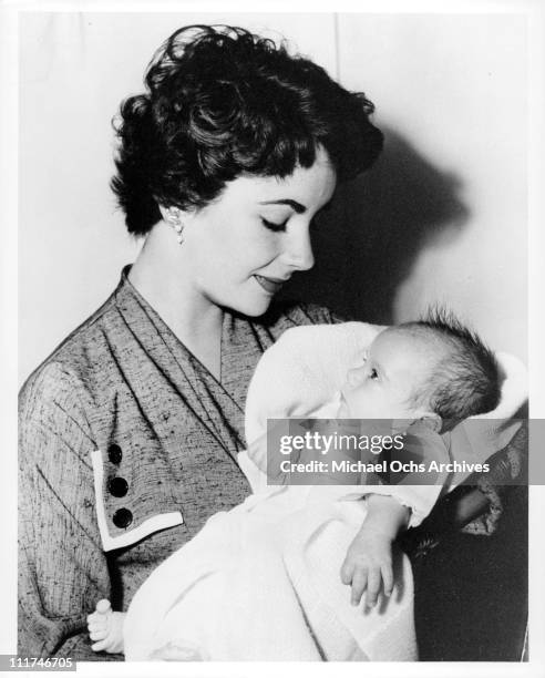 Actress Elizabeth Taylor holding baby Michael Wilding, Jr. In her arms, 1953.
