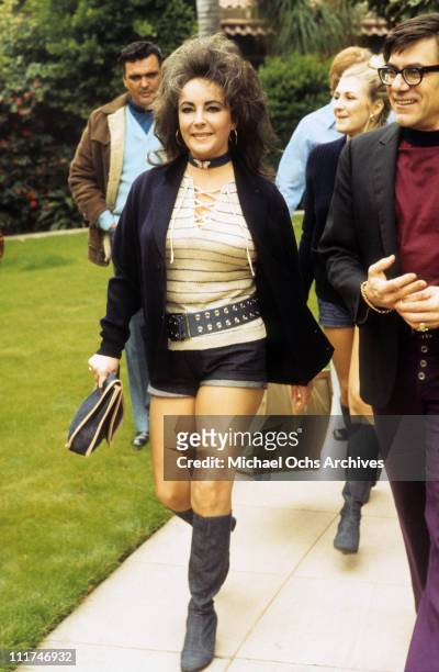 Actress Elizabeth Taylor walking outdoors in short denim shorts and boots, March 1971.