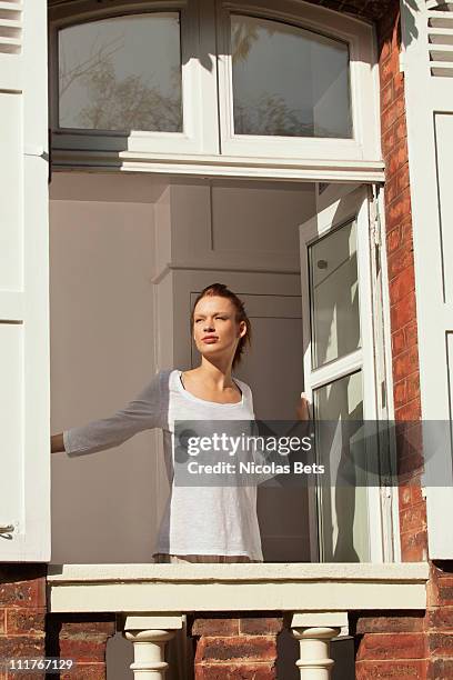 young woman opening window - fenster offen stock-fotos und bilder