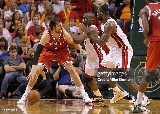 Andrew Bogut of the Milwaukee Bucks posts up Joel Anthony and LeBron James of the Miami Heat during a game at American Airlines Arena on April 6,...