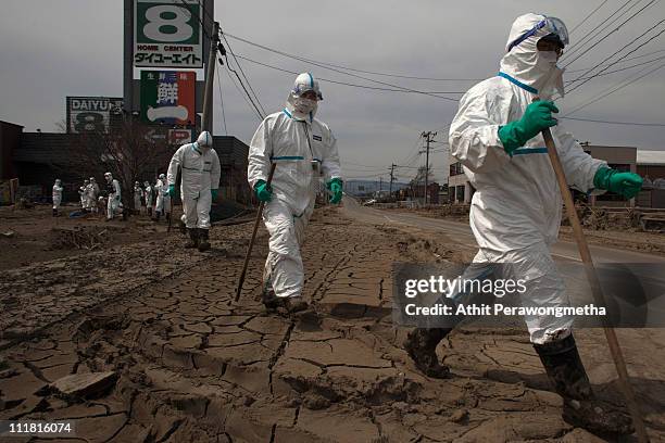 Japanese Police wearing protective suits search for tsunami victims within the exclusion zone, about 12 miles away from Fukushima Nuclear Power Plant...