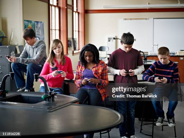 group of students on smart phones in classroom - cell phones in school stock pictures, royalty-free photos & images