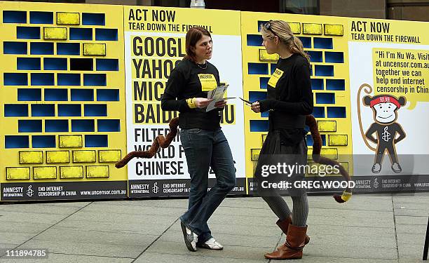 Amnesty International members stand in front of a yellow wall during an event in Sydney on July 30, 2008 as part of a campaign to end internet...