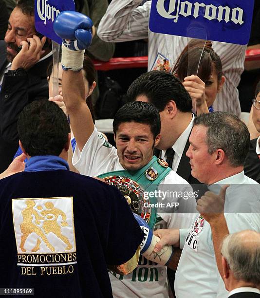 Challenger Jhonny Gonzalez of Mexico raises his arm in the air as he receives tha champion's belt of the WBC featherweight title bout in Kobe in...