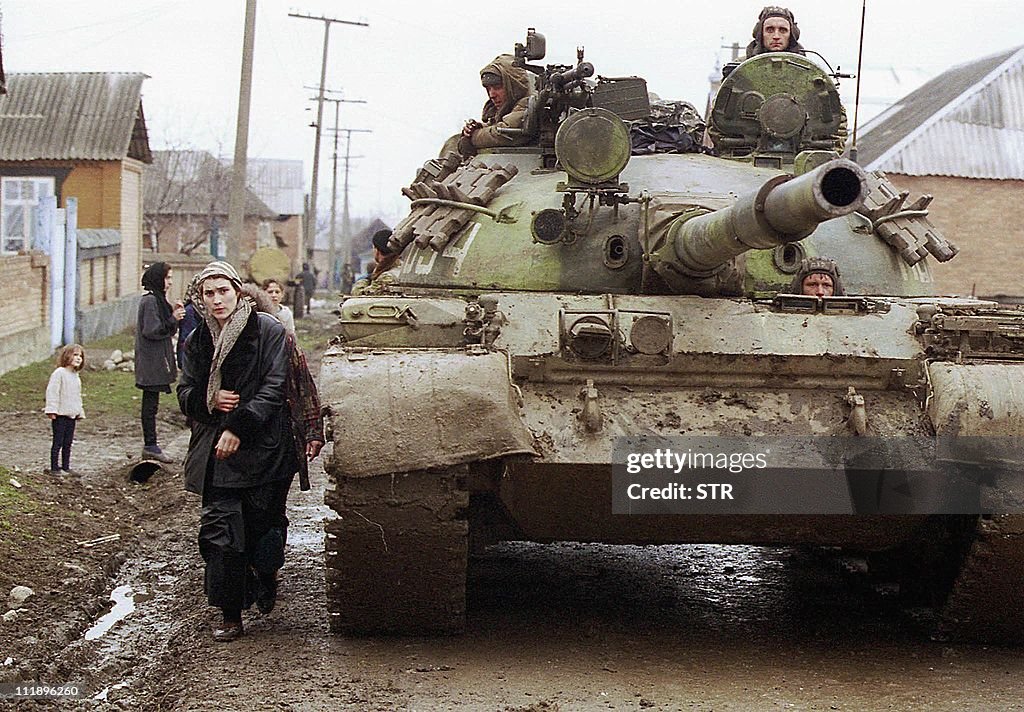 A Chechen woman passes by a tank of Russ
