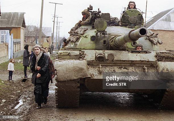 Chechen woman passes by a tank of Russian federal troops on the main street of Gehy-Chu village, south from Grozny 16 February 2000. Russian forces...