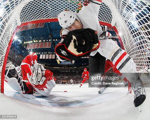 Viktor Stalberg of the Chicago Blackhawks crashes into the back of the net as Jimmy Howard of the Detroit Red Wings defends the goal during an NHL...