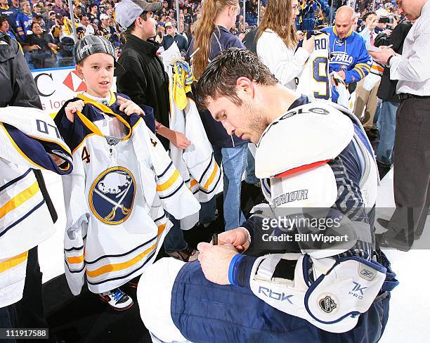Steve Montador of the Buffalo Sabres signs an autograph for a young fan as he and his teammates give away their game jerseys following their 4-3 win...