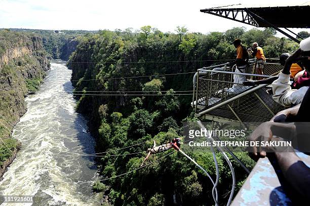 This picture taken on April 1, 2011 shows people watching a man bungee jumping in Victoria Falls, Zimbabwe. Zimbabwe's tourism earnings jumped 47...