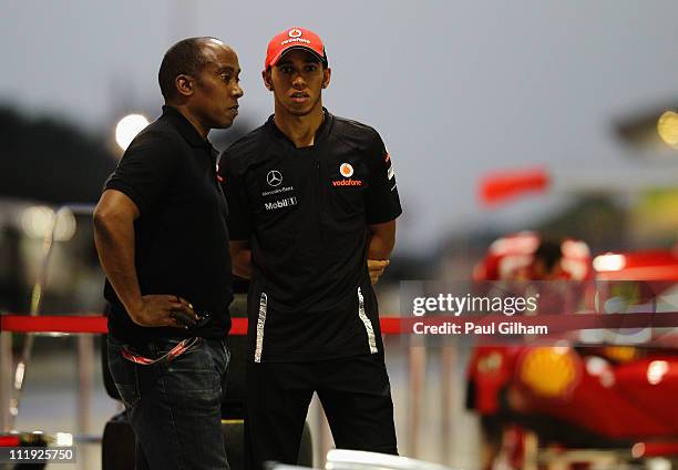 Lewis Hamilton of Great Britain and McLaren and his father Anthony Hamilton talk outside the McLaren team garage following qualifying for the...