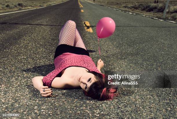 young woman with is laying on the road holding balloon - emo girl stock pictures, royalty-free photos & images