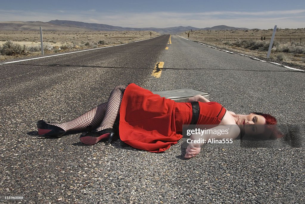 Mujer joven con es establecer lifelessly en la carretera