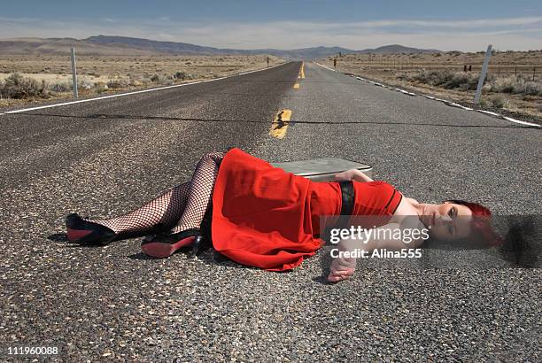 young woman with is laying lifelessly  on highway - dead women stockfoto's en -beelden