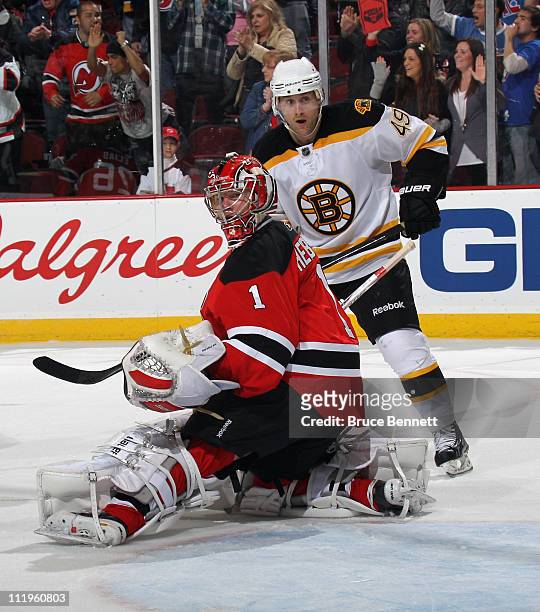Rich Peverley of the Boston Bruins and Johan Hedberg of the New Jersey Devils watch a shot go wide of the net at the Prudential Center on April 10,...