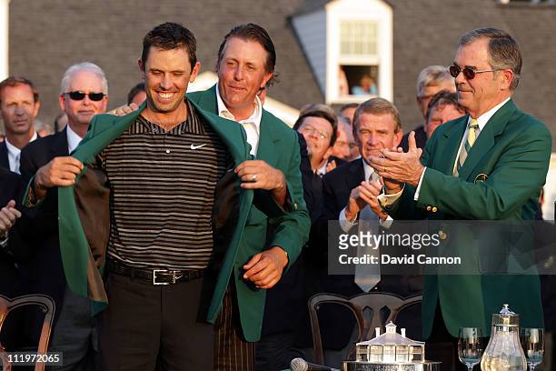 Phil Mickelson presents Charl Schwartzel of South Africa the winner's jacket at the green jacket presentation as William Porter Payne looks on after...
