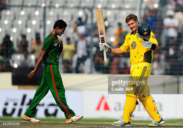 Australian batsman Shane Watson raises his bat after scoring a century as Bangladehsi bowler Shafiul Islam walks on the grounds during the second...