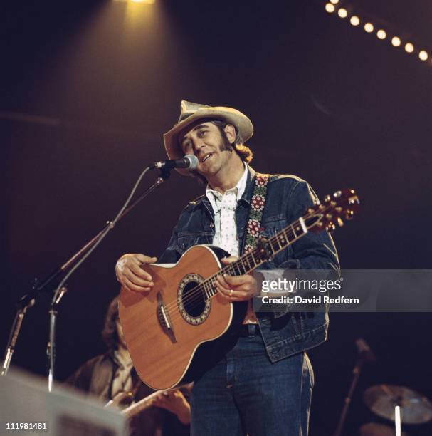 Don Williams, U.S. Country singer, in concert, playing a guitar and singing into a microphone, circa 1975.