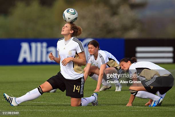 Dzsenifer Maroszan and Kerstin Garefrekes watch Kim Kulig juggle with the ball during a training session of the German Women's national football team...